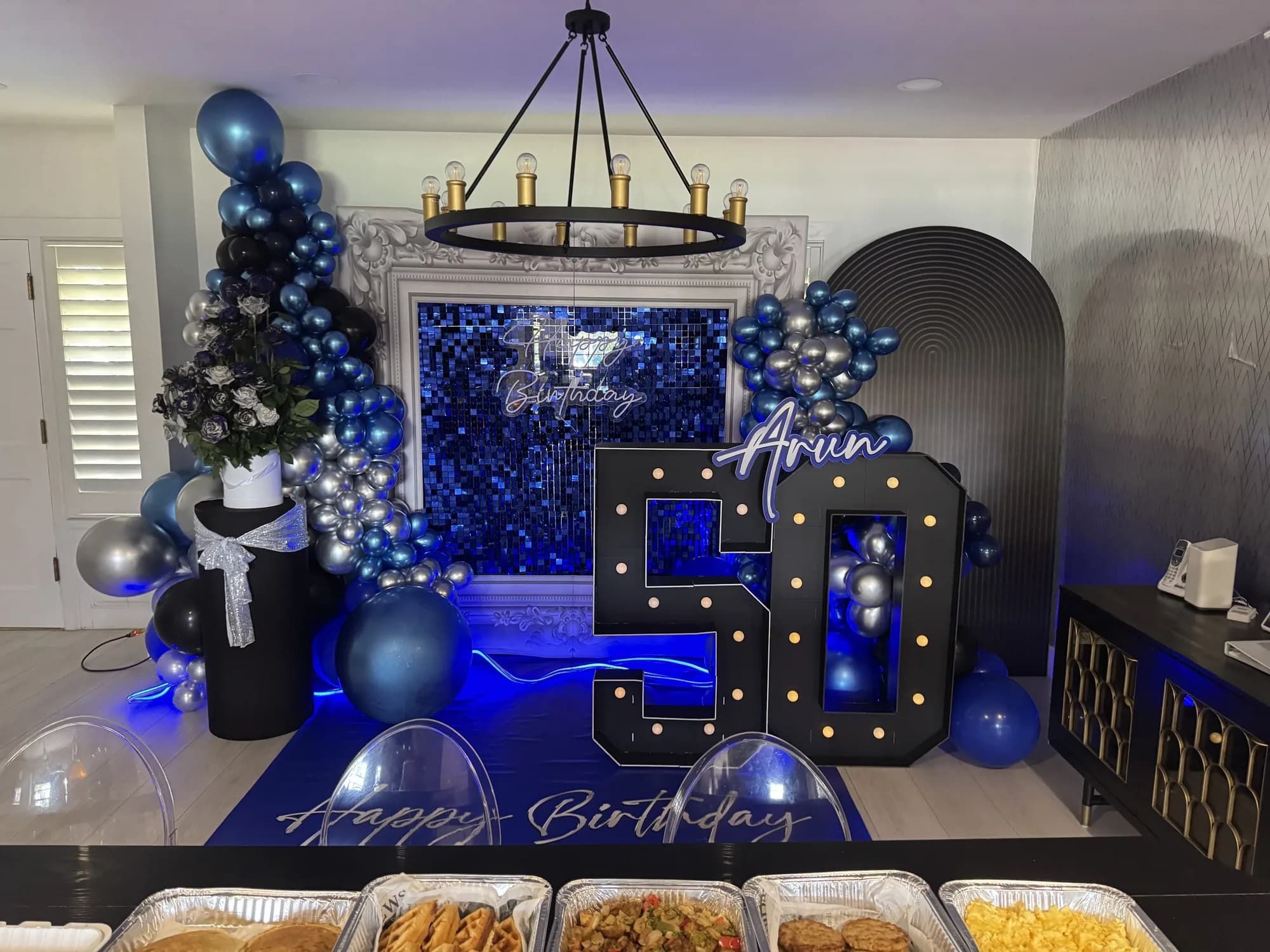 Lit marquee numbers and balloons at a 50th birthday party
