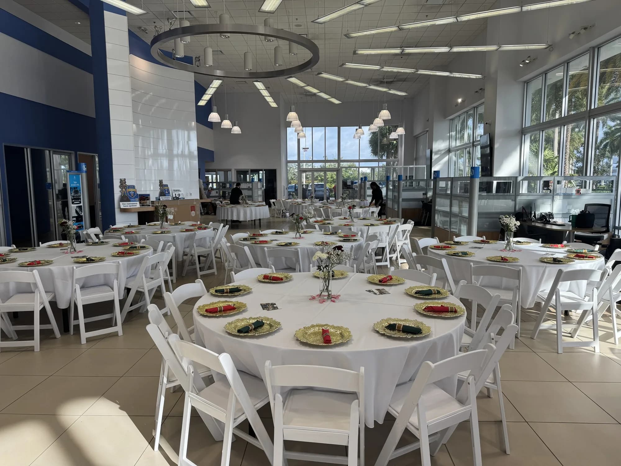 Banquet room with white chairs and round tables set for a corporate dinner
