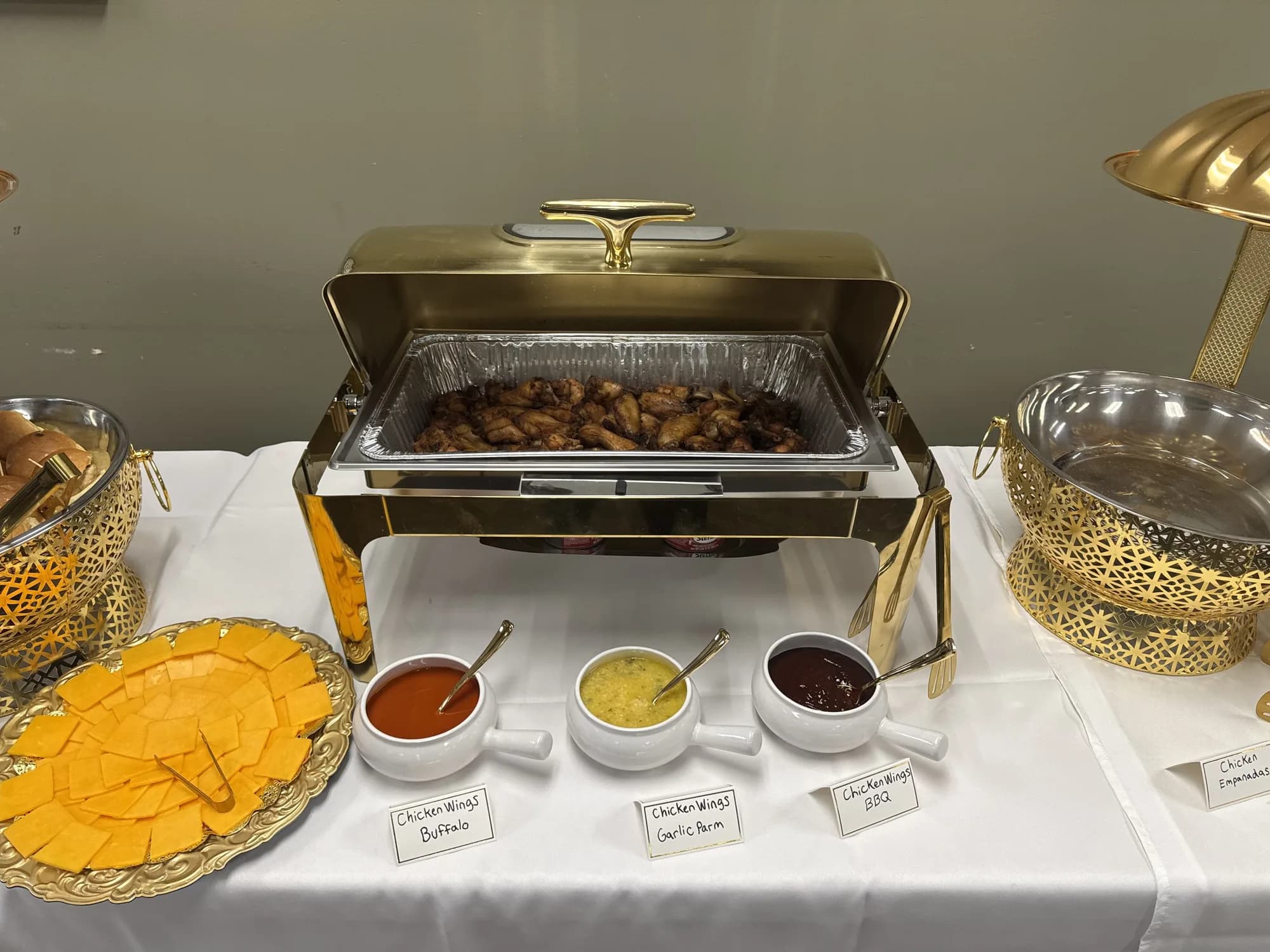 Chafing dishes with sauces and sides on a white buffet
