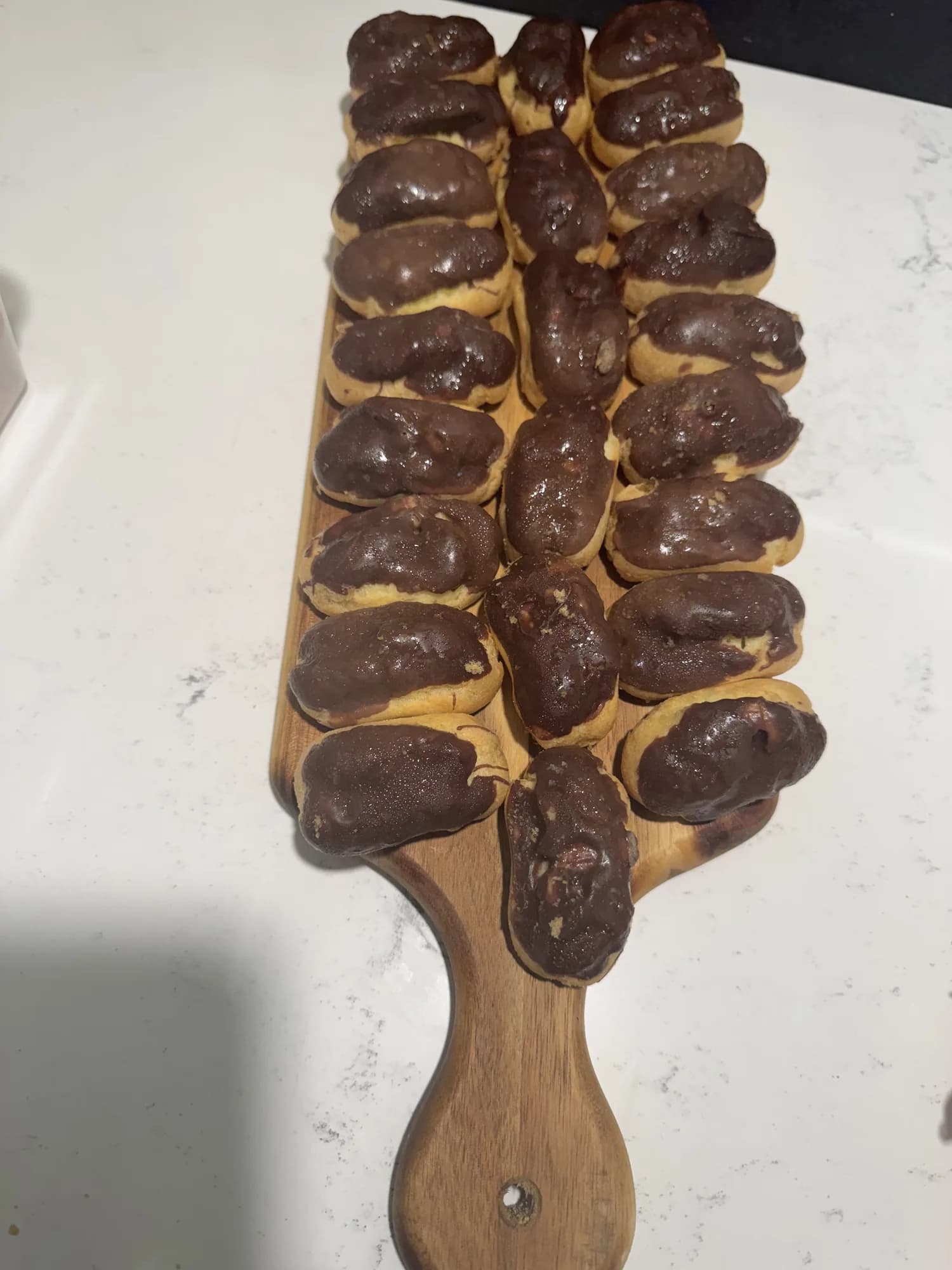 Chocolate éclairs on a wooden serving board