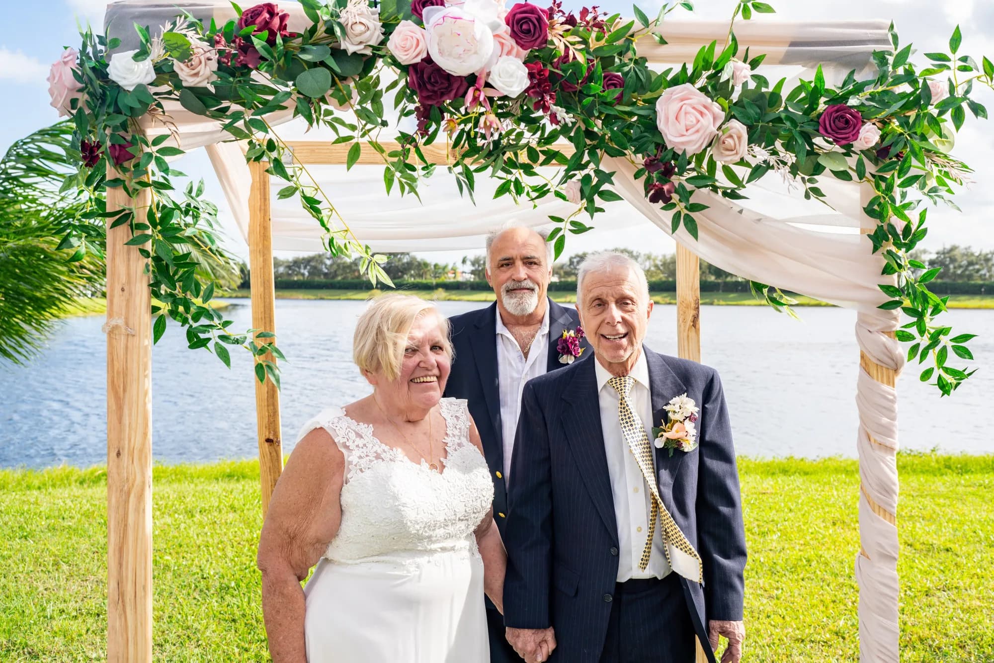 Couple at a floral arch by the lake