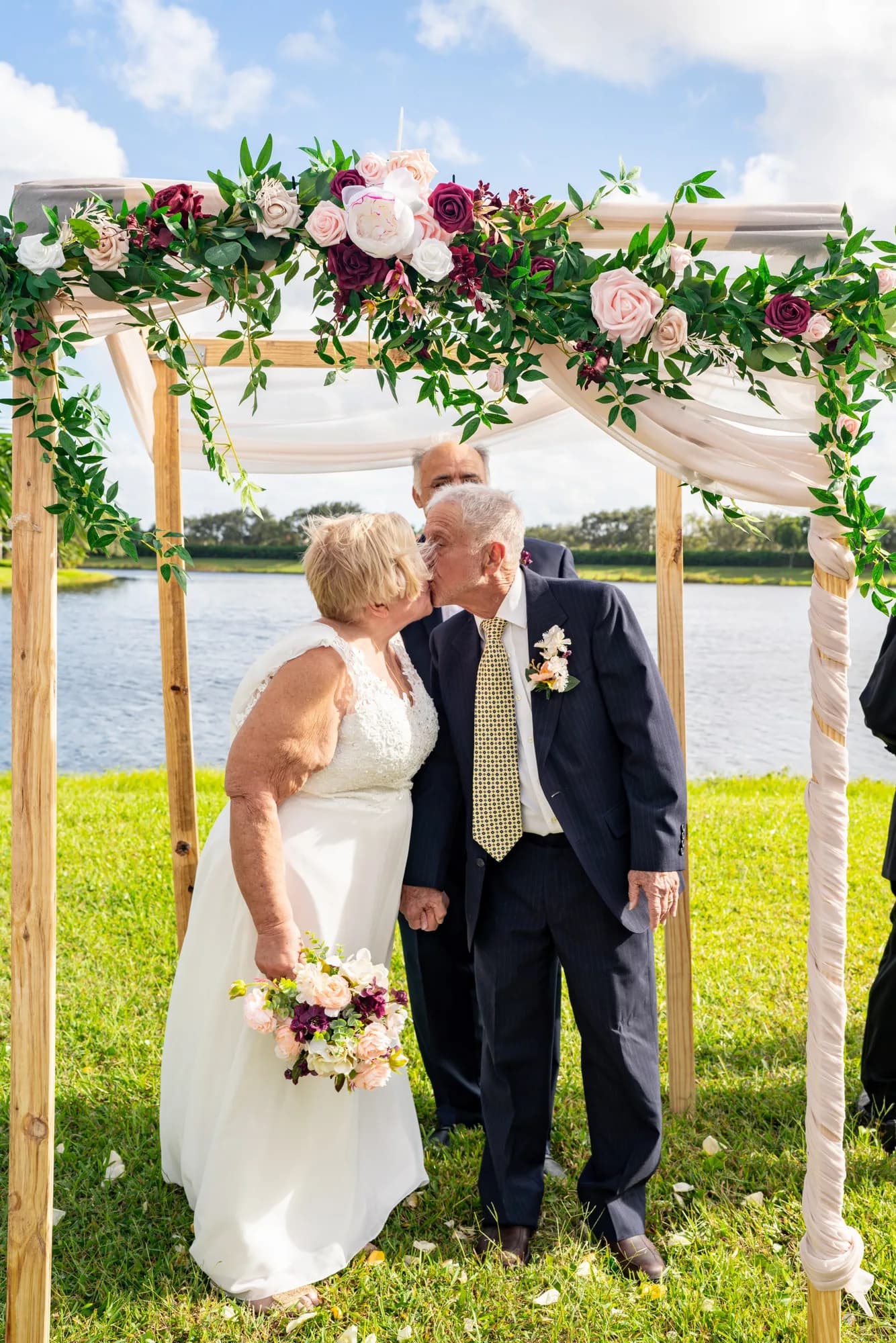 Couple kissing under a floral wedding arch