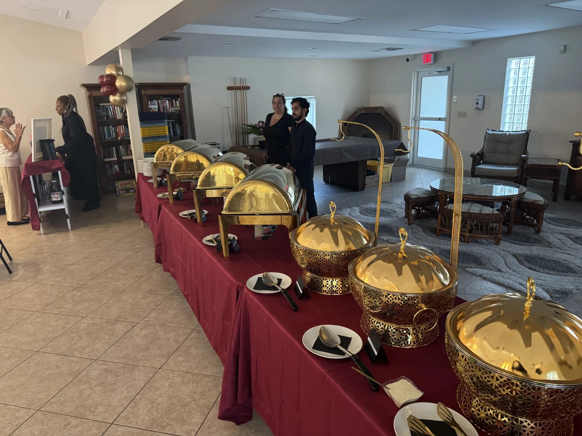 Gold chafing dishes on a burgundy buffet at a birthday luncheon