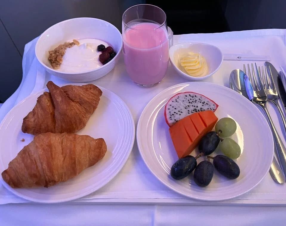 Breakfast tray: croissants, yogurt with granola and berries, fresh fruit and a berry smoothie