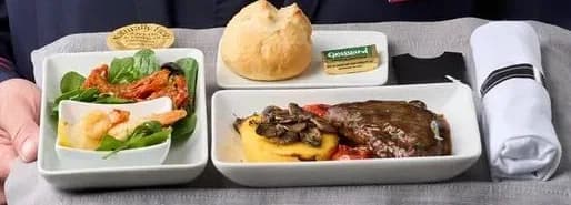 Tray presented with salad, steak over polenta and a roll