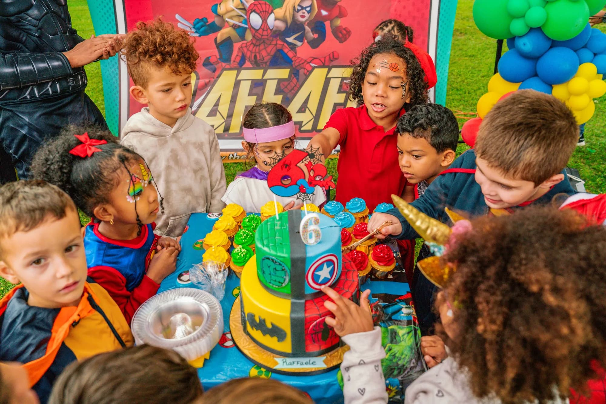 Kids gathered around a superhero cake