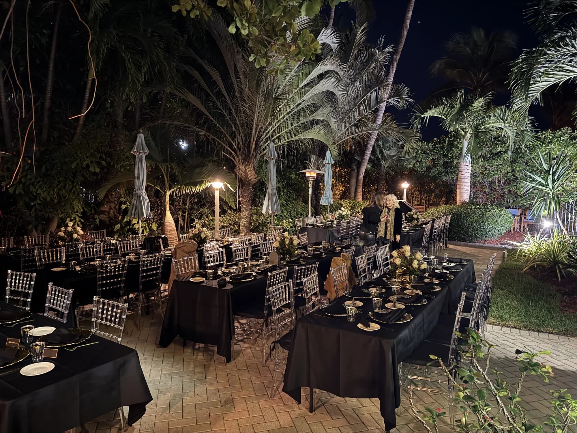 Outdoor dinner tables beneath palms in South Florida