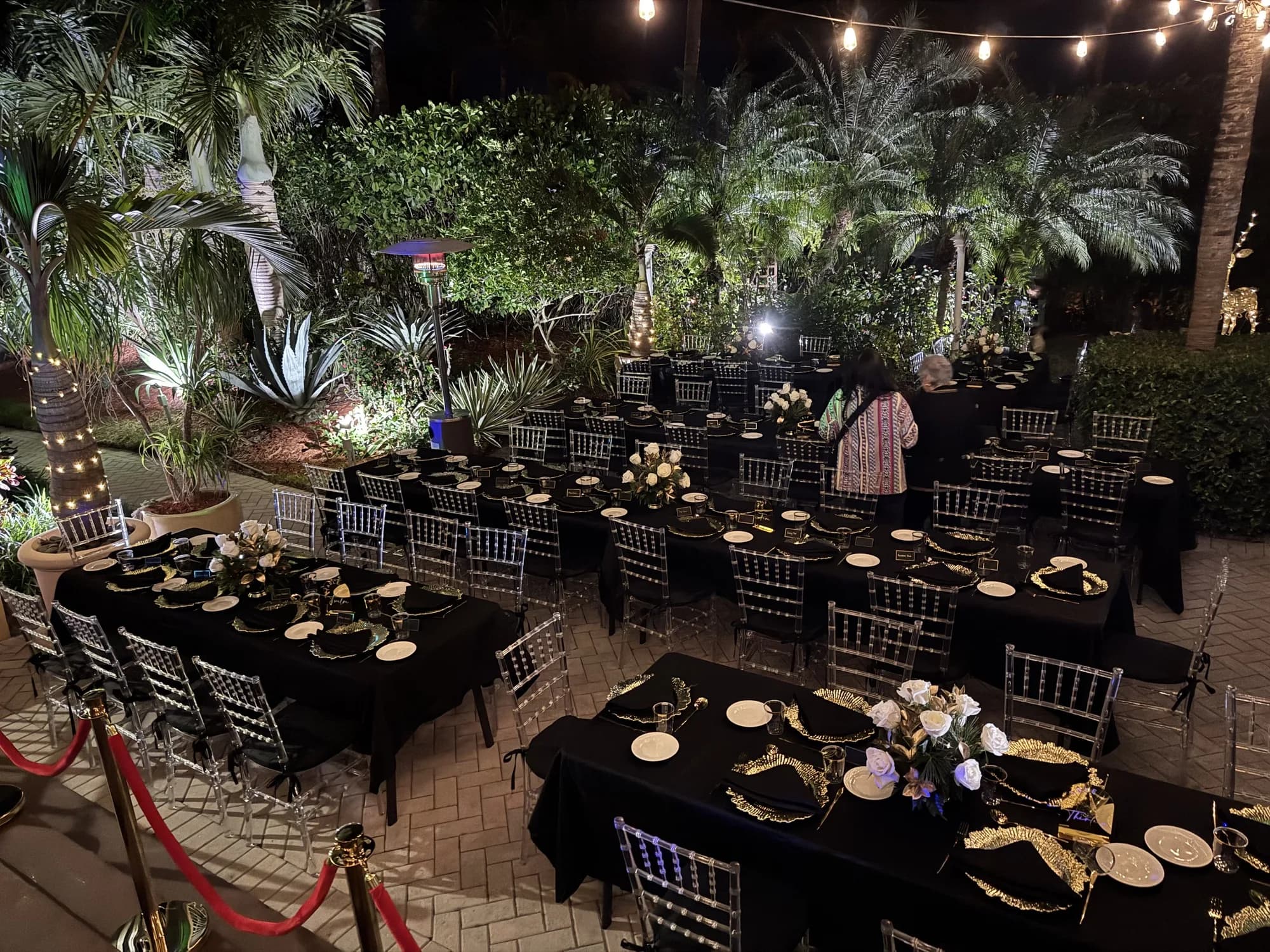 Outdoor evening garden dinner with black chairs and string lights