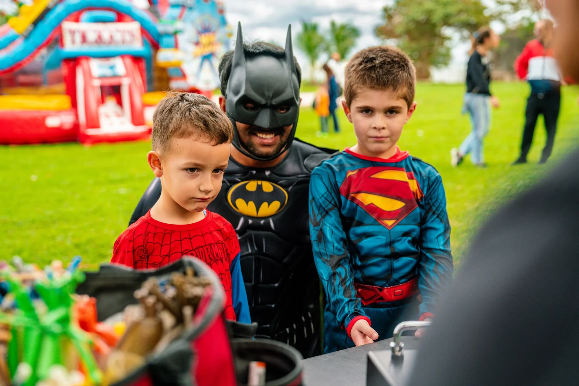 Kids in superhero costumes at an outdoor birthday party